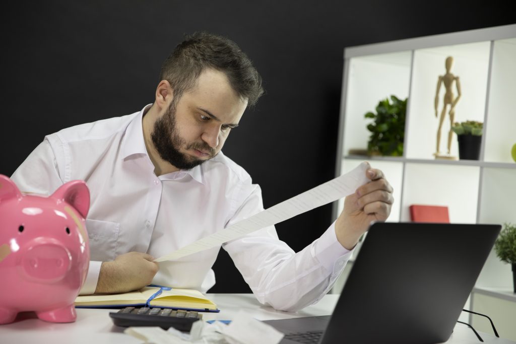Frustrated business owner looking on long bills on his hands